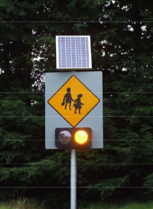 This image shows a School Ahead sign with flashing amber lights
